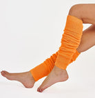 Woman wearing bright plain orange ribbed knit leg warmers.