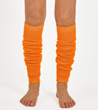 Woman wearing bright plain orange ribbed knit leg warmers.